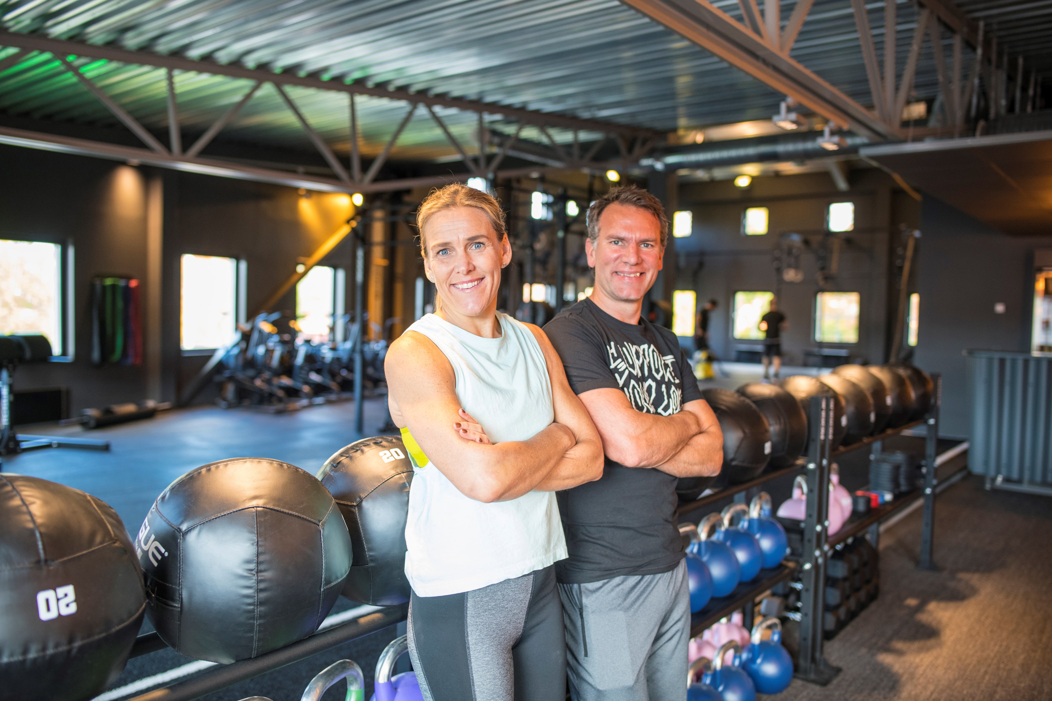 Anna och Ronnie poserar framför ett ställ med medicinbollar